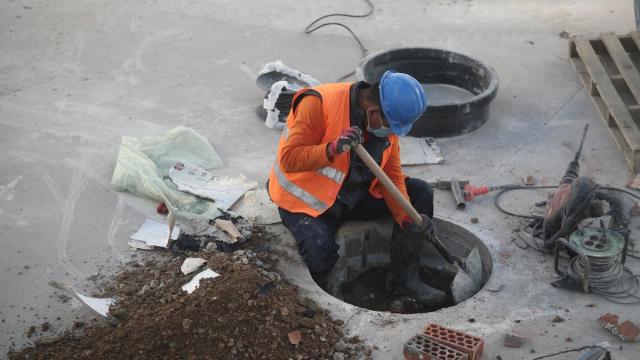 Un obrero trabaja en una alcantarilla.