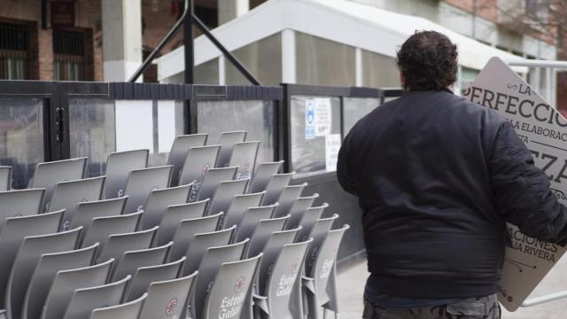 Un hostelero coloca sillas en una terraza.