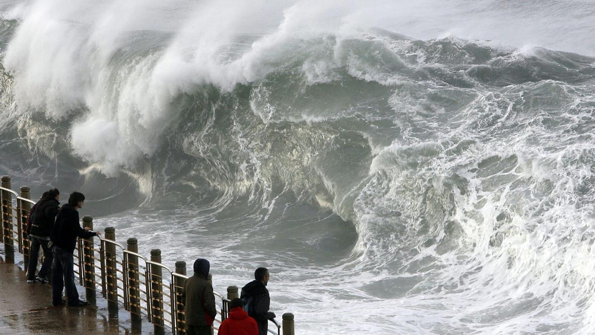 Varias personas contemplan la fuerza del mar en el Paseo Nuevo de Donosti.