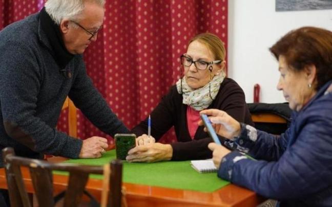 Varias personas mayores con sus móviles.