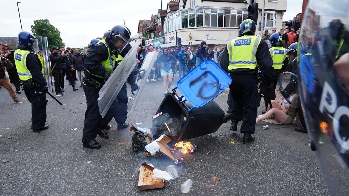 Un grupo de personas lanza un cubo de basura a la policía británica durante los disturbios en Middlesbrough, Reino Unido, en 2024.