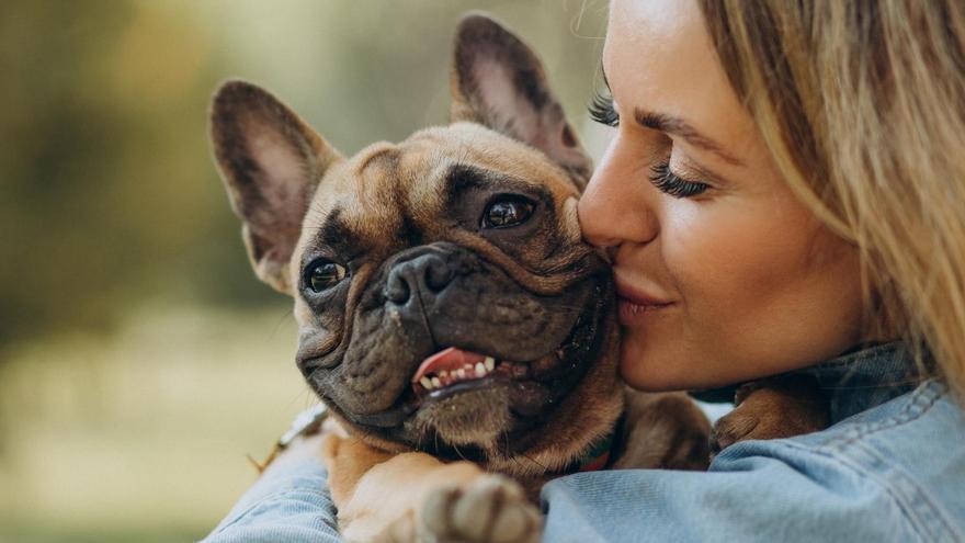 Una mujer abraza a su bulldog francés de ojos marrones