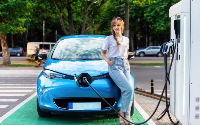 Una joven recarga su coche eléctrico en una instalación en la calle.