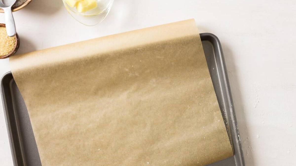 Papel para hornear sobre una bandeja de horno con varios ingredientes alrededor