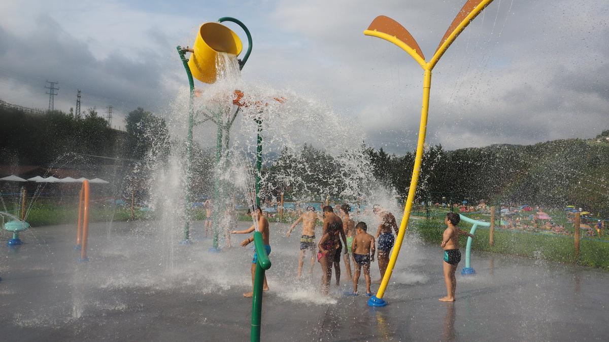 Un grupo de niños se divierte y se refresca en la zona de chorros de agua de Mintxeta.