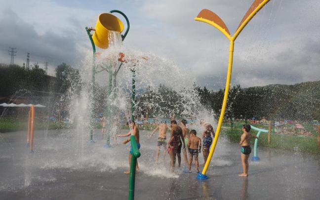 Un grupo de niños se divierte y se refresca en la zona de chorros de agua de Mintxeta.