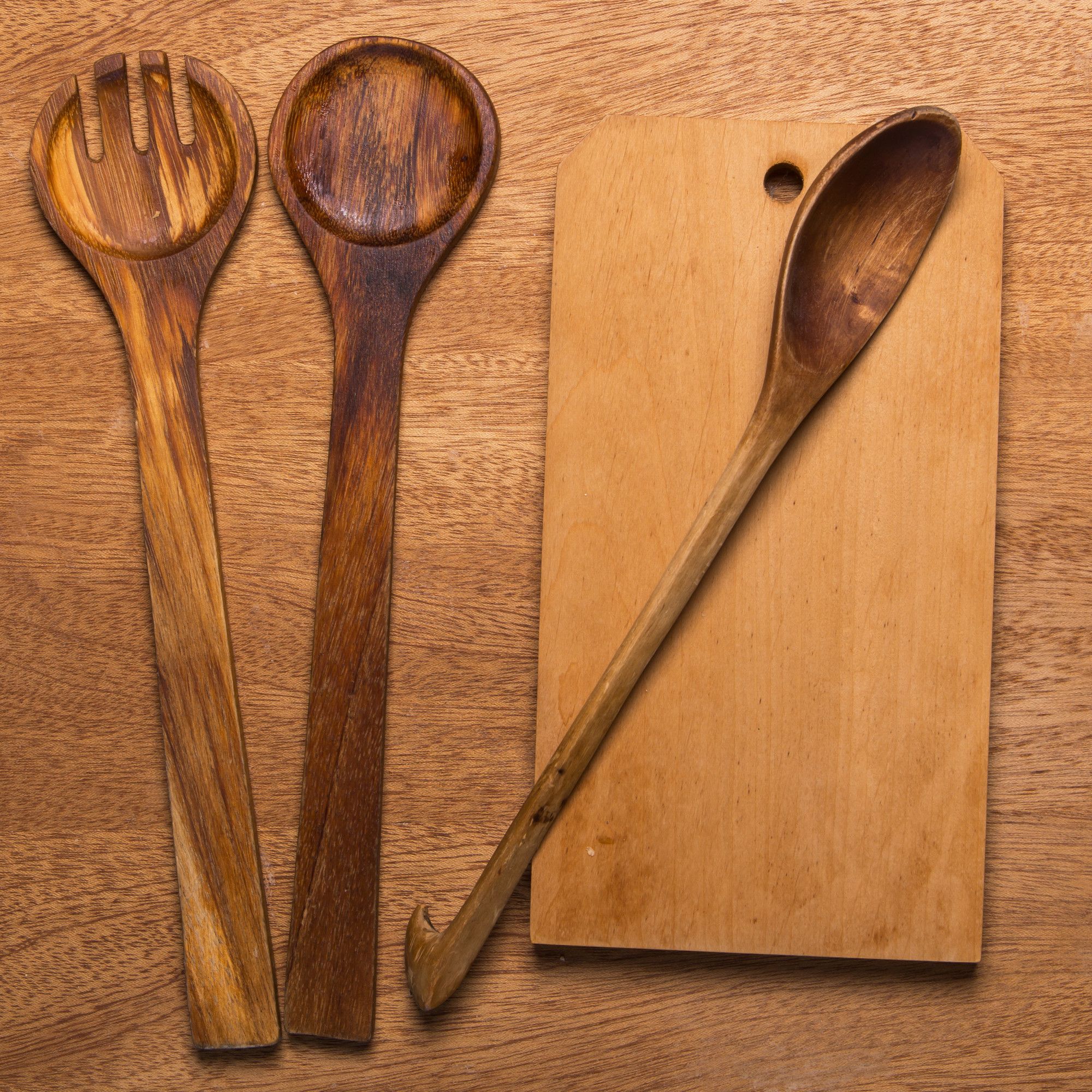 Cubiertos de madera junto a una tabla para cortar alimentos.