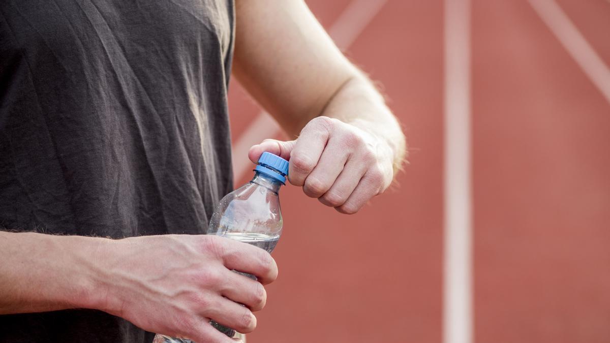 Un atleta abre una botella de plástico.