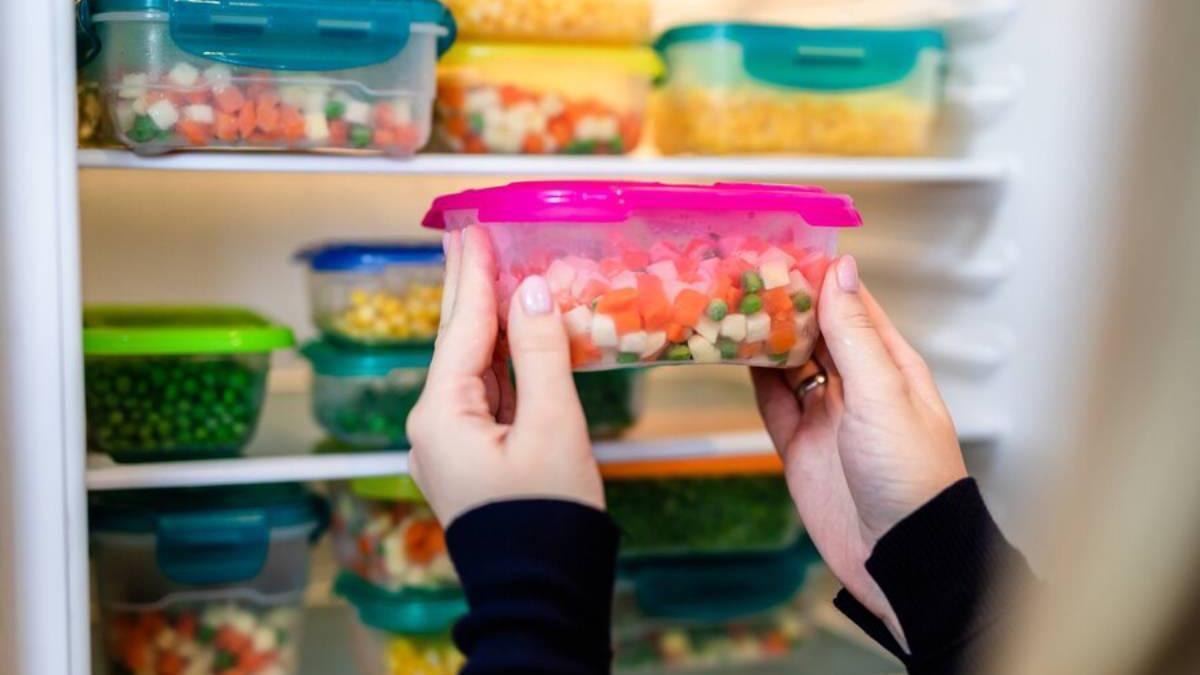 Mujer guarda un taper con verduras en la nevera