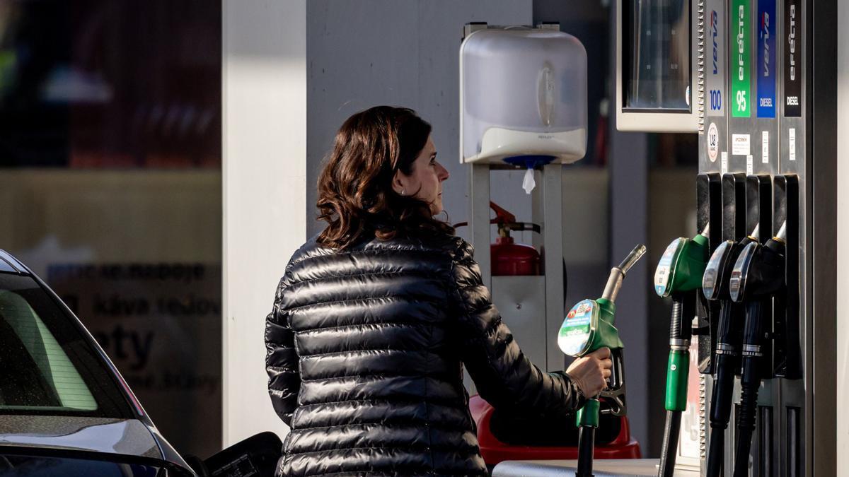 Una mujer reposta en una gasolinera.