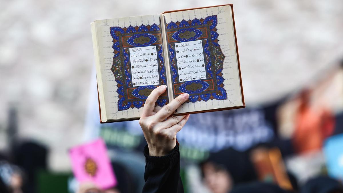 Un manifestante alza una copia del Corán contra la quema de ejemplares del libro sagrado del islam en Suecia.