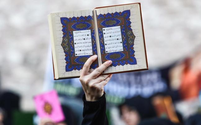 Un manifestante alza una copia del Corán contra la quema de ejemplares del libro sagrado del islam en Suecia.