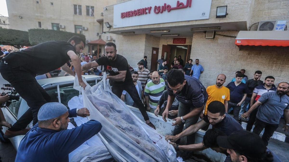 Un grupo de palestinos traslada los cuerpos de dos personas asesinadas en un ataque israelí.