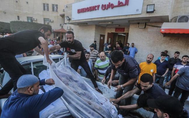 Un grupo de palestinos traslada los cuerpos de dos personas asesinadas en un ataque israelí.