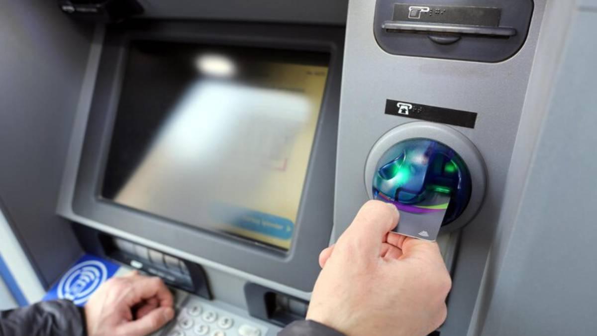 Hombre retira la tarjeta de crédito del cajero automático una vez finalizada la transacción