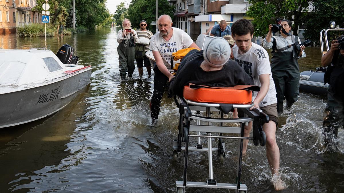 Voluntarios empujan una camilla médica en Jersón, Ucrania, tras la destrucción de la presa Kajovka.