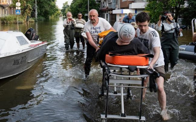 Voluntarios empujan una camilla médica en Jersón, Ucrania, tras la destrucción de la presa Kajovka.