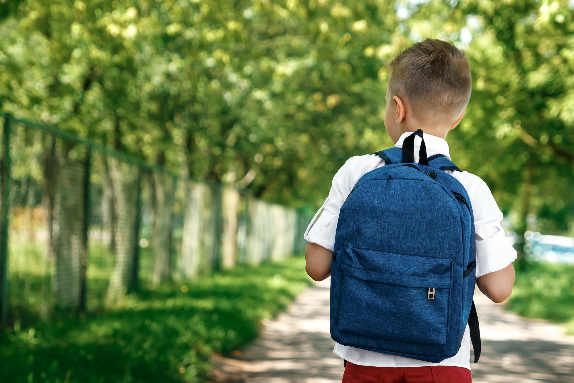Niño de espaldas con una mochila de color azul.