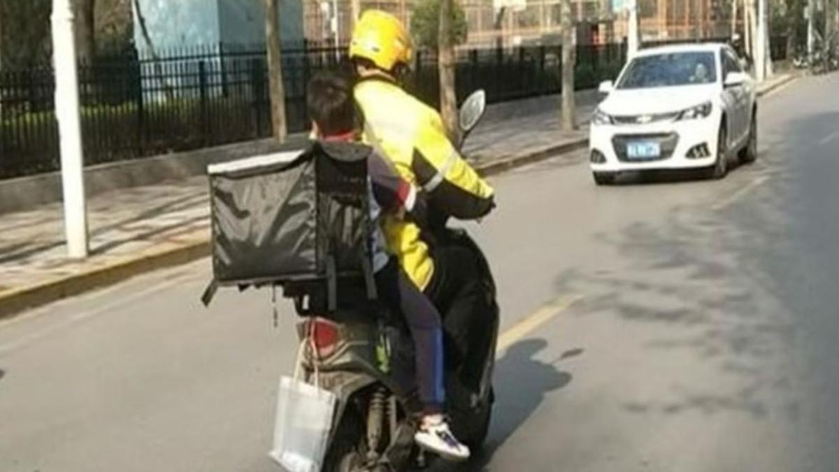 Un repartidor, transportando a un niño.