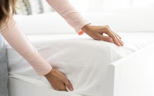 Manos de una chica haciendo la cama por la mañana.