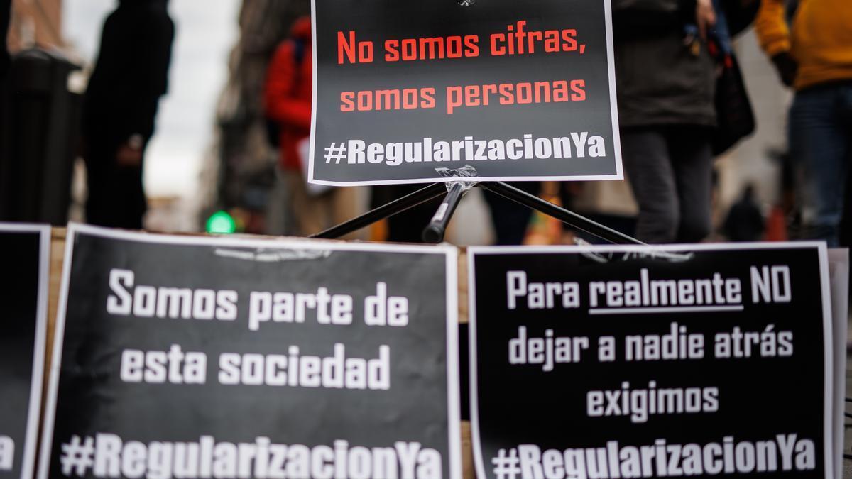 Varias pancartas en una concentración para exigir la regularización de las personas inmigrantes en situación irregular.