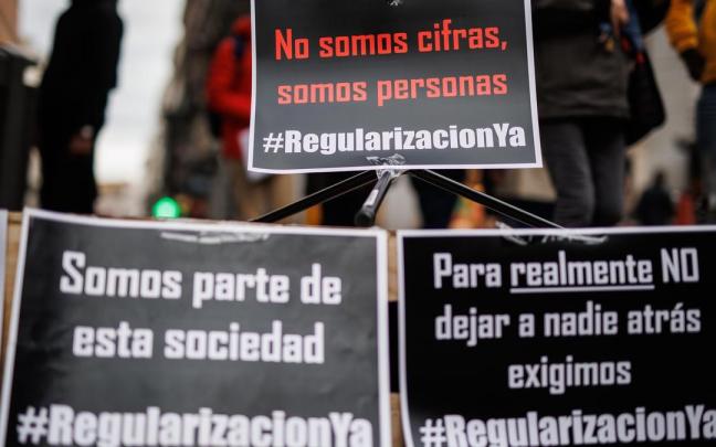 Varias pancartas en una concentración para exigir la regularización de las personas inmigrantes en situación irregular.