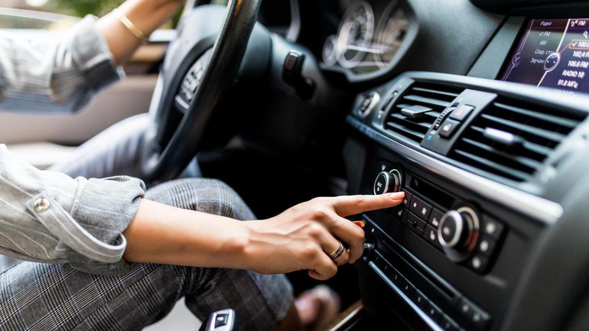 Chica enciende la radio del coche mientras conduce.