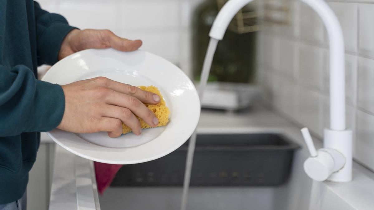 Manos de un hombre fregando los platos