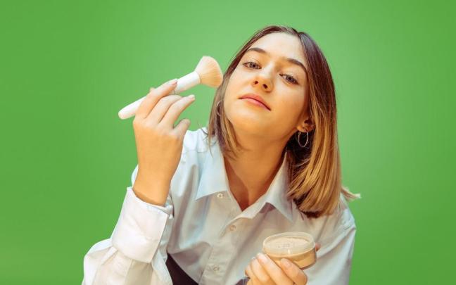 Una mujer se aplica maquillaje en el rostro. Una mujer se aplica maquillaje en el rostro.