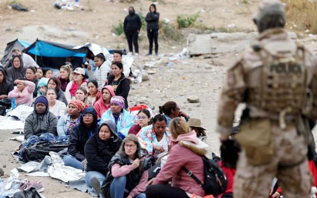 Un grupo de migrantes solicitantes de asilo espera para ser trasladado en San Diego, California.