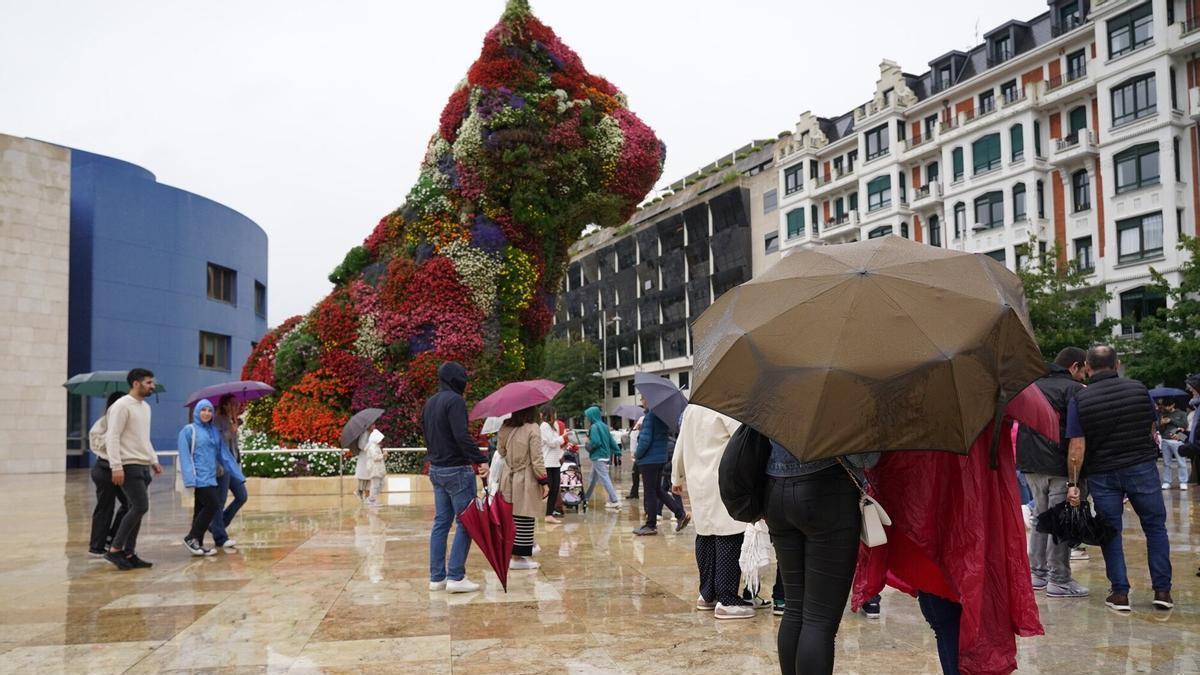 Turistas un día de lluvia frente al Puppy del Museo Guggenheim de Bilbao.