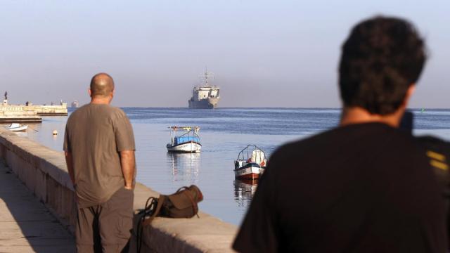 Dos personas observan un barco de ayuda humanitaria procedente de México en el puerto de La Habana.