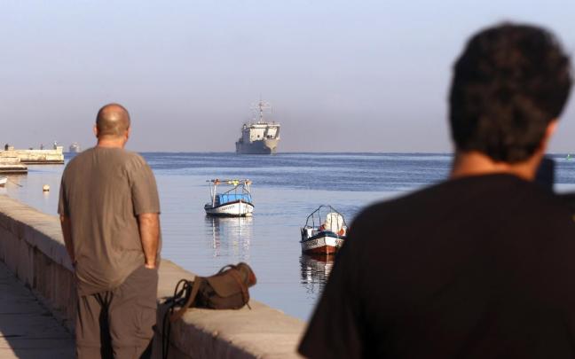 Dos personas observan un barco de ayuda humanitaria procedente de México en el puerto de La Habana.