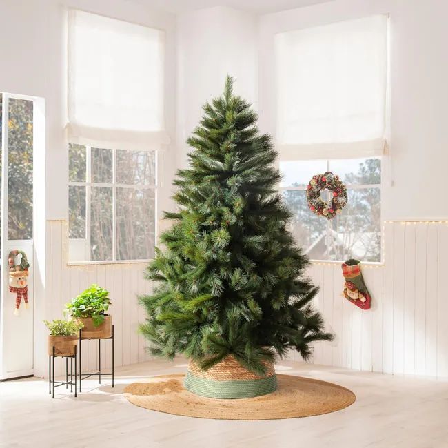 Pino de Navidad con la base cubierta por una pieza de rafia.