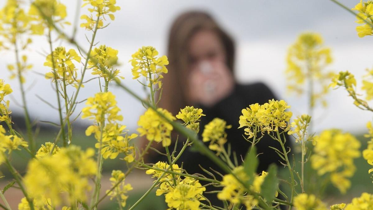 Una joven alérgica al polen sonándose la nariz.