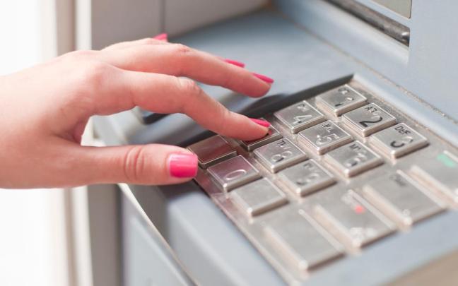 Una mujer realiza una operación bancaria en un cajero.