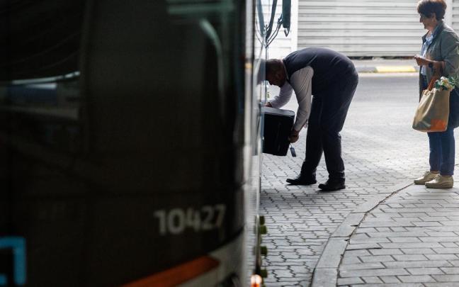 Viajeros depositando sus maletas en el maletero de un autobús.