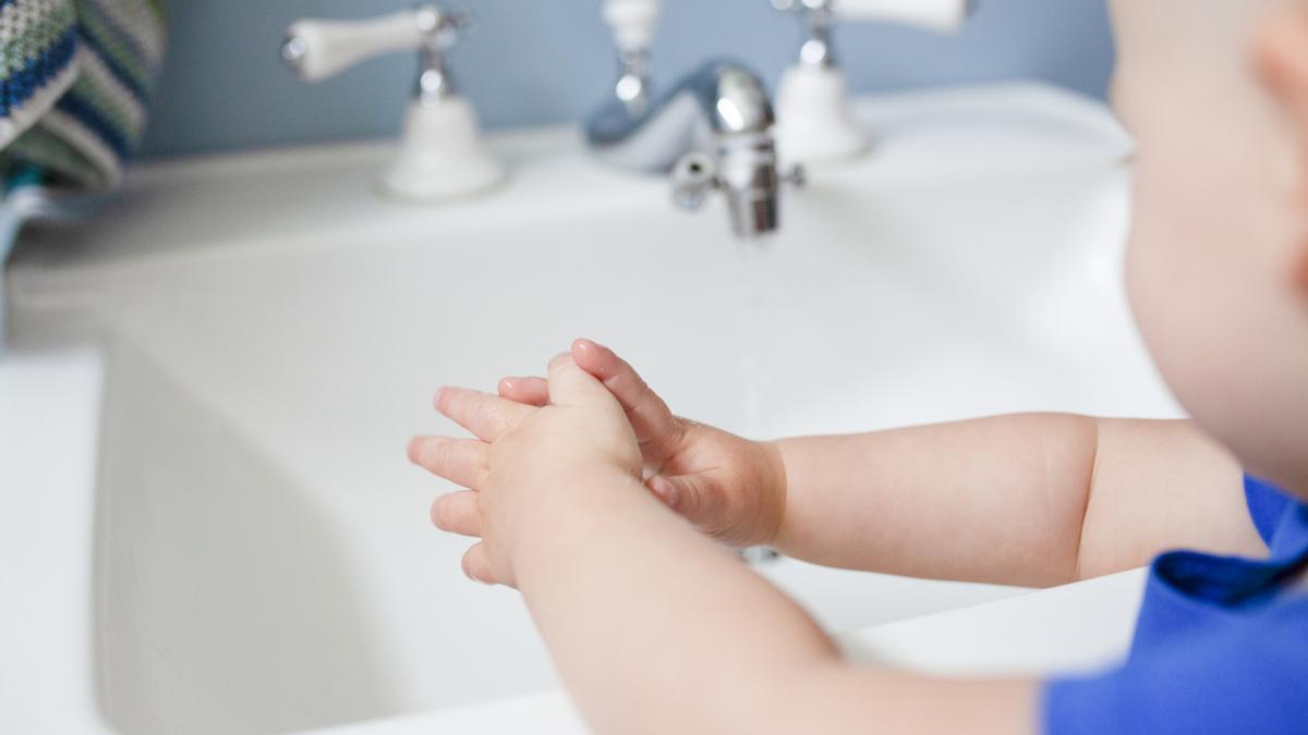 Imagen de un bebé con las manos mojadas frente a un lavabo