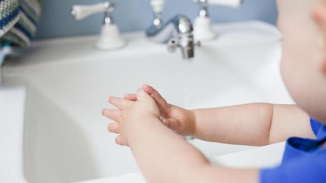 Imagen de un bebé con las manos mojadas frente a un lavabo