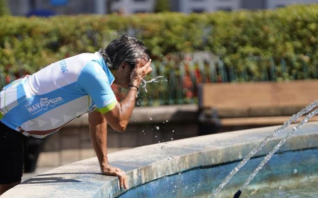 Un ciclista se refresca en una fuente de Oviedo.