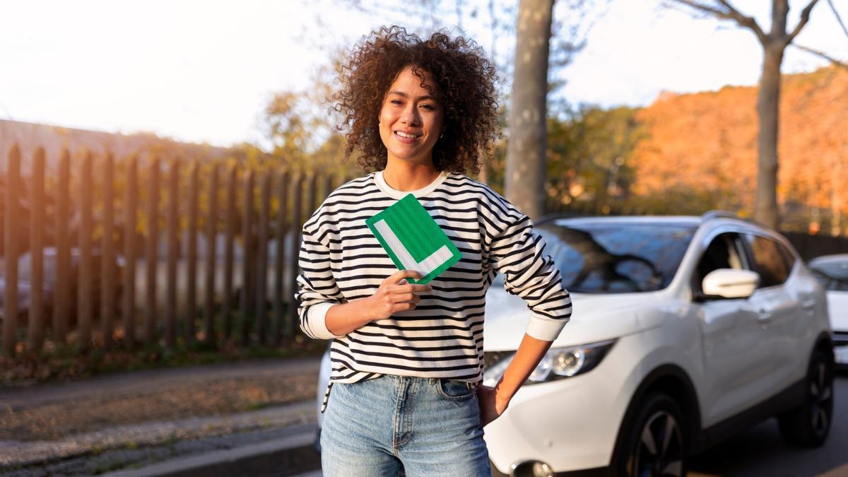 Una joven posa con la placa que acredita que es conductora novel.