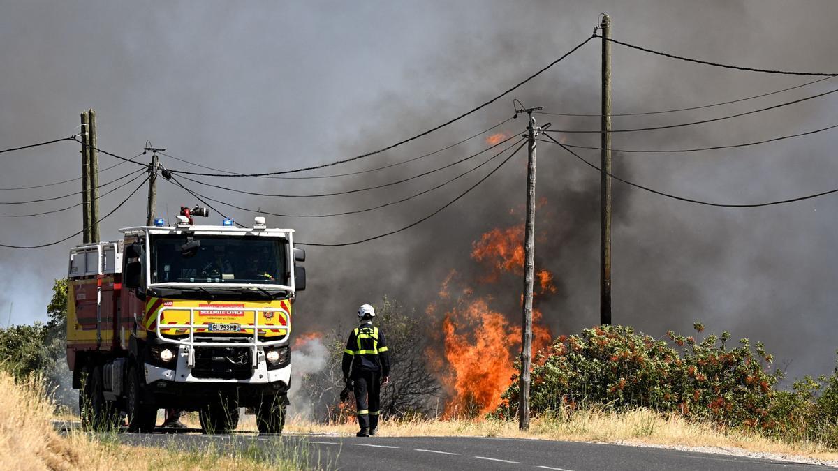 Un bombero de la Agencia de Protección Civil francesa camina por una carretera junto a un incendio forestal cerca de Ille-sur-Tet.