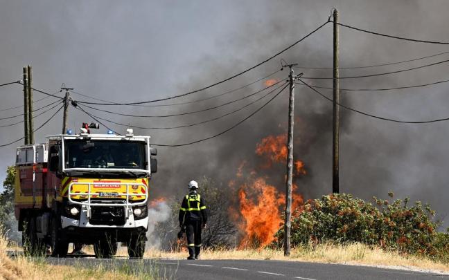 Un bombero de la Agencia de Protección Civil francesa camina por una carretera junto a un incendio forestal cerca de Ille-sur-Tet.