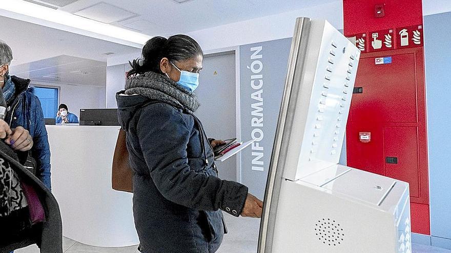 Una mujer con mascarilla pide cita en un centro hospitalario.