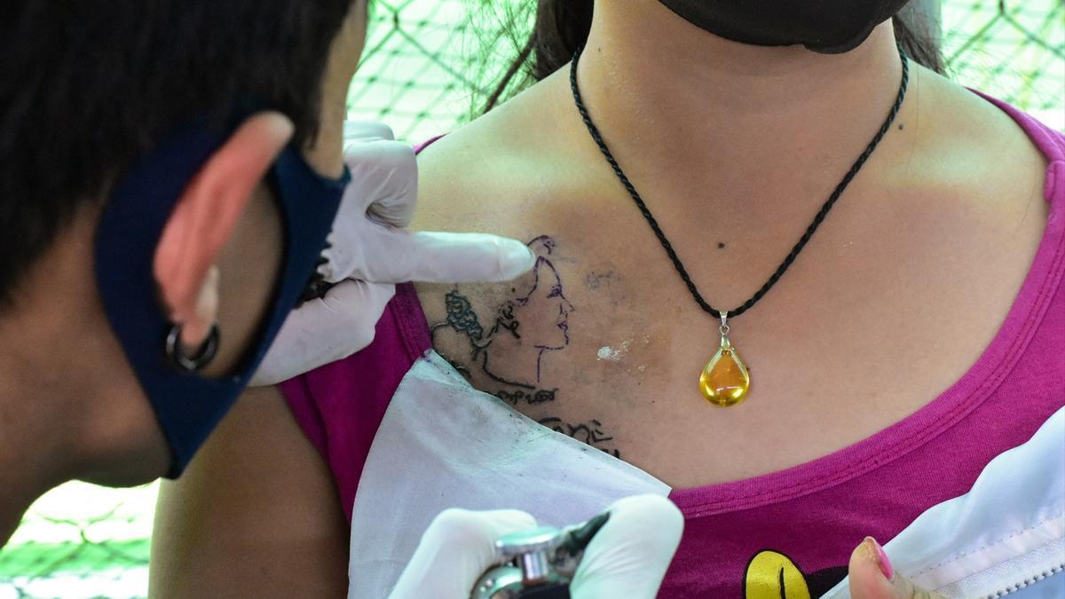 Artista del tatuaje trabajando en el retrato de una mujer