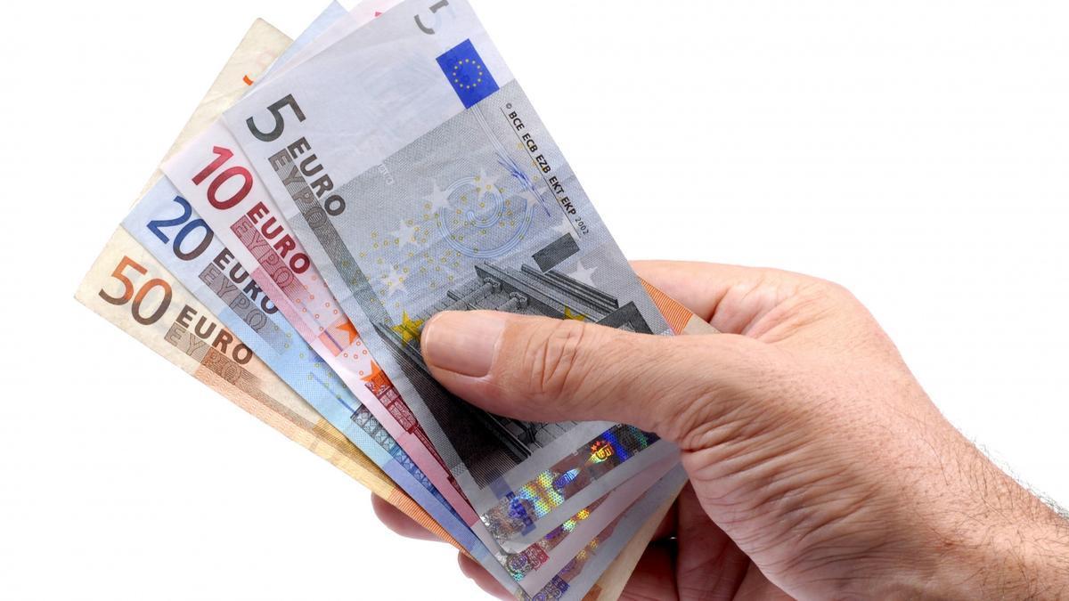Una mano sujeta varios billetes de euro de distinto valor.