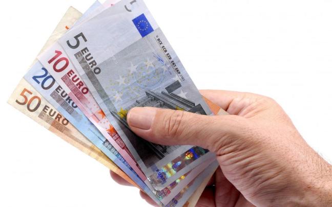Una mano sujeta varios billetes de euro de distinto valor.