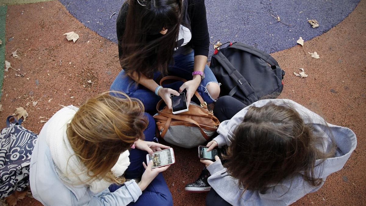 Un grupo de chicas, ajenas a esta información, con sus teléfonos móviles.