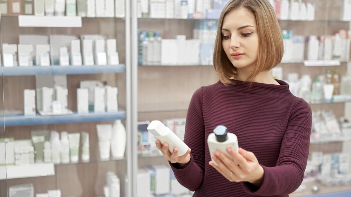 Una mujer revisa los componentes de dos champús.