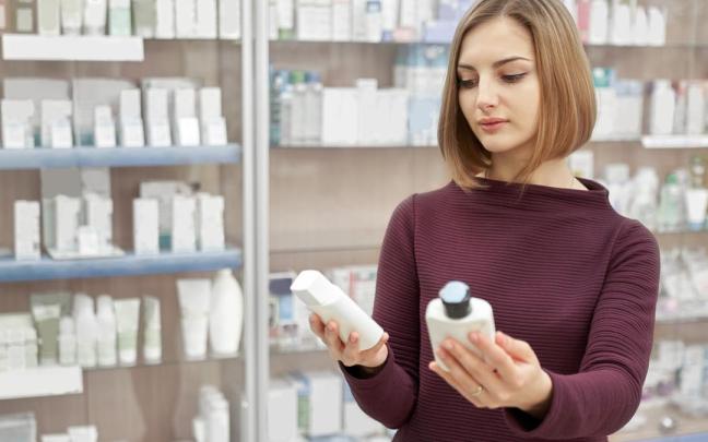 Una mujer revisa los componentes de dos champús.